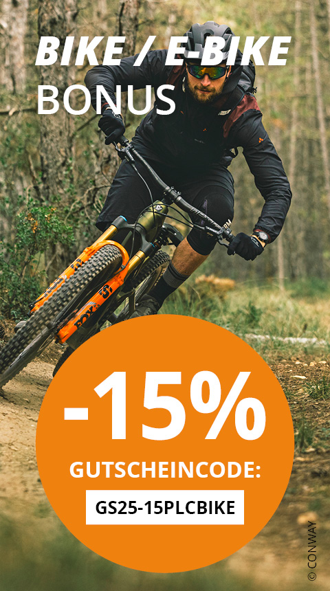 Ein Radfahrer in Jacke und Helm fährt mit einem Mountainbike durch einen Waldweg. Der Text lautet „Bike/E-Bike Bonus“, „-15% Gutscheincode: GS25-15PLCBBIKE“. Im Hintergrund sind Bäume und Blätter zu sehen.