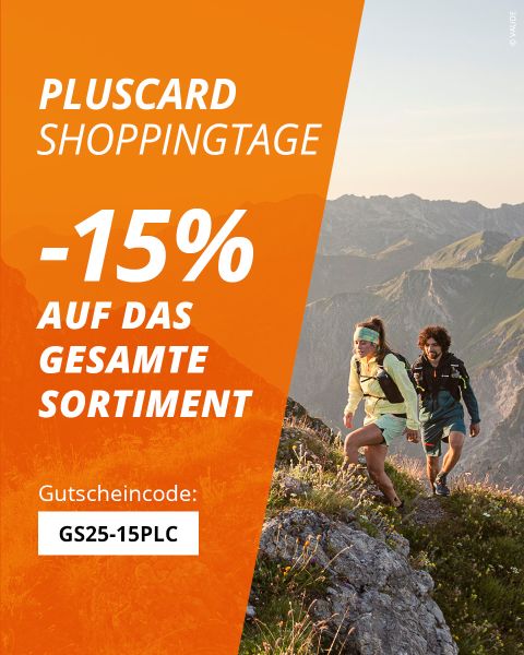 Zwei Personen wandern auf einem felsigen Berg mit malerischer Aussicht auf sanfte Hügel. Ein orangefarbenes Banner bietet mit „PLUSTCARD SHOPPINGTAGE“ und dem Code „GS25-15PLC“ 15% Rabatt auf das gesamte Sortiment.