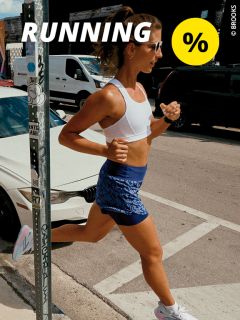 Eine Frau in Sportkleidung läuft im Sonnenlicht auf einem Bürgersteig. Sie trägt einen weißen Sport-BH, blaue Shorts und eine Sonnenbrille. Über ihr erscheinen das Wort „RUNNING“ und ein gelbes Prozentzeichen. Im Hintergrund sind Autos und Gebäude zu sehen.