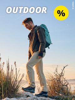 Ein Mann mit Rucksack wandert bei Sonnenuntergang durch felsiges Gelände, umgeben von trockenem Gras. Am Himmel sind das Wort „OUTDOOR“ und ein gelbes Prozentzeichen zu sehen.