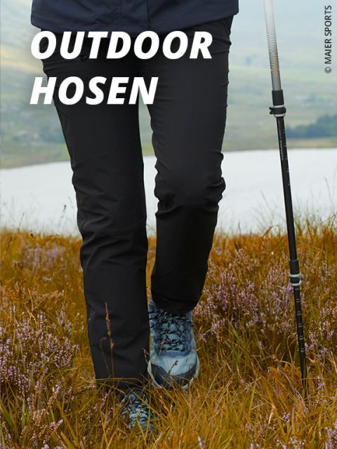 Eine Person in schwarzer Outdoor-Hose und blauen Wanderschuhen läuft mit einem Trekkingstock durch eine Wiese. Der Text "OUTDOOR HOSEN" erscheint in fetten weißen Buchstaben oben links.