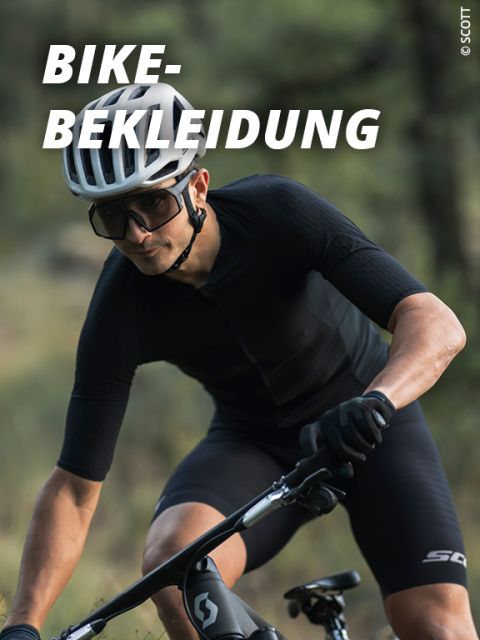 Ein Radfahrer, der einen Helm, eine Sonnenbrille und schwarze Radsportkleidung trägt, fährt im Freien Fahrrad. Großer weißer Text quer über das Bild lautet "BIKE-BEKLEIDUNG". Der Hintergrund ist verschwommene Natur.