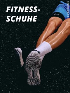 Eine Person in Sporthosen, weißen Socken und gemusterten Fitnessschuhen sitzt auf einem gesprenkelten Turnhallenboden. Der fettgedruckte Text lautet "FITNESS-SCHUHE". Das Bild hebt die Schuhe und Beine in einer sportlichen Umgebung hervor.
