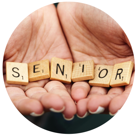Die Hände halten Scrabble-Steine, die das Wort "SENIOR" ergeben.