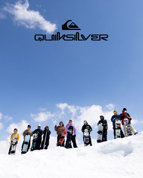 Ein Surfer reitet auf einer großen türkisfarbenen Welle und verkörpert Balance und Können. Er trägt dunkle Badeshorts, und die Welle kräuselt sich über ihm. Über ihm ist das Quiksilver-Logo zu sehen.
