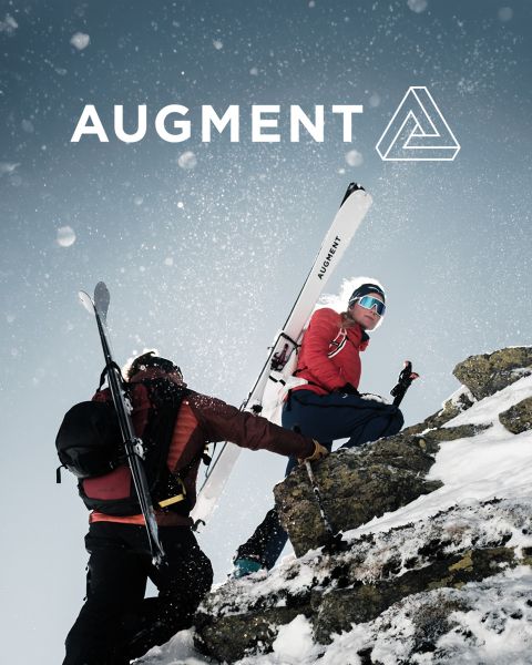 Zwei Skifahrer in Winterausrüstung und mit Skiern erklimmen einen verschneiten, felsigen Berghang unter einem bewölkten Himmel. Das Wort "AUGMENT" und ein geometrisches Logo erscheinen am oberen Rand des Bildes. Um sie herum fallen Schneeflocken.