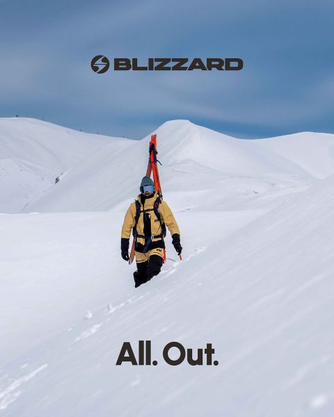 Zwei Skifahrer in Winterkleidung fahren einen schneebedeckten Hang hinunter. Der linke Skifahrer trägt ein rosa Outfit, der rechte ein beiges. Beide tragen Helme und Schutzbrillen. Das Blizzard-Logo ist oben links zu sehen.