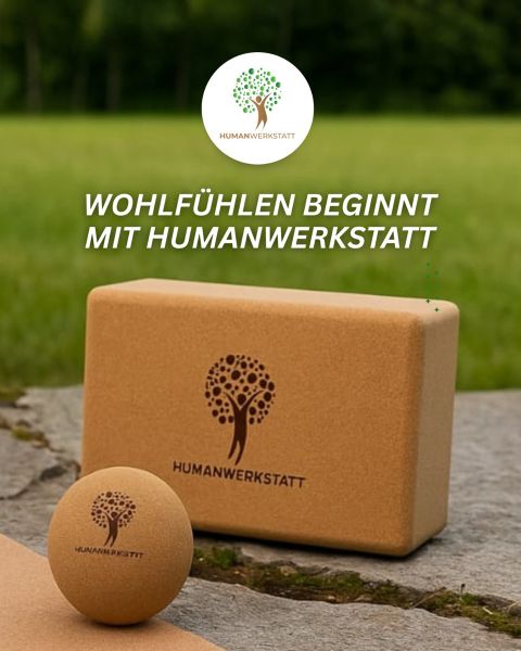 Ein Yogablock aus Kork und ein Massageball mit dem Logo der Humanwerkstatt auf Gras. Darüber steht ein weißer Text in deutscher Sprache: "WOHLFÜHLEN BEGINNT MIT HUMANWERKSTATT.