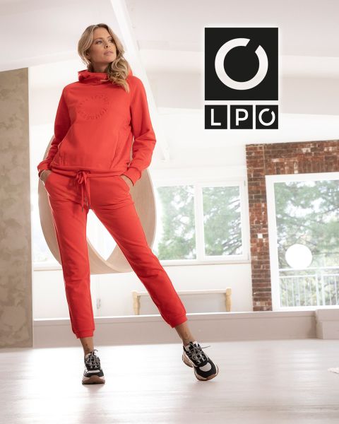 Ein Mann in blauem T-Shirt und dunkler Hose macht in einem Fitnessstudio im Industriestil mit zwei großen Bogenfenstern im Hintergrund eine Battle Rope-Übung. Licht fällt herein und in der oberen rechten Ecke erscheinen die Buchstaben „LPO“.