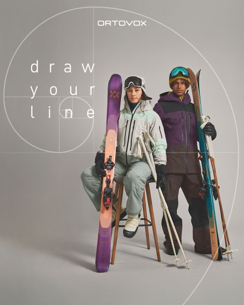 Drei Personen in Outdoor-Ausrüstung sitzen lächelnd und unterhalten sich auf felsigem Gelände in einer Bergregion. Die Sonne versinkt hinter den Gipfeln. Ein Rucksack und eine Thermoskanne stehen in der Nähe. Das Logo von Ortovox befindet sich oben rechts.