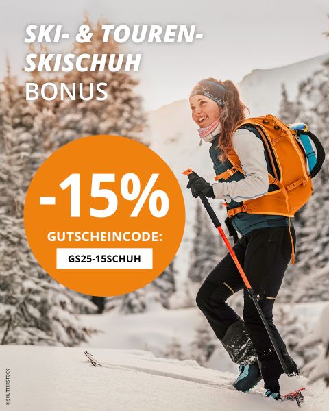 Nahaufnahme einer Person im Schnee, die blaugrüne Skischuhe mit der Aufschrift „Atomic“ zurechtrückt. Ein orangefarbener Kreis zeigt „-15% Gutscheincode: GS25-15SCHUH“ und wirbt für einen Ski- und Tourenschuhbonus. Unten sind schneebedeckte Skier zu sehen.