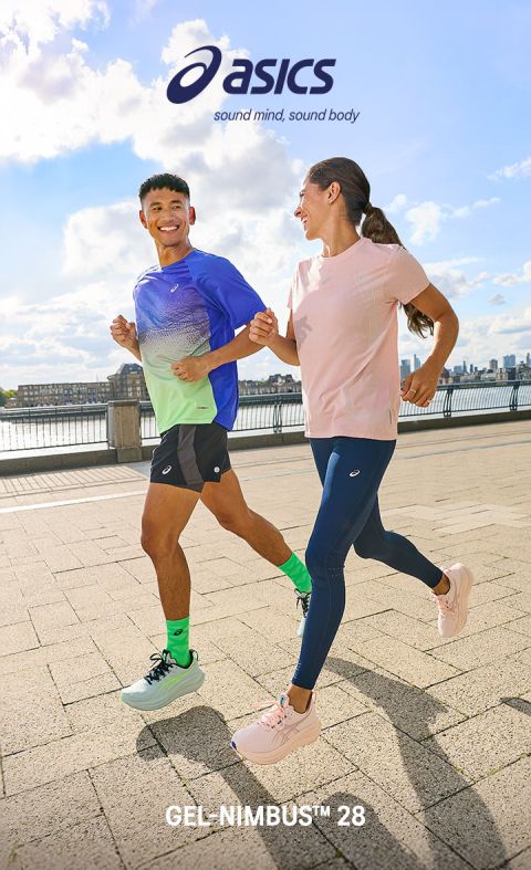 Zwei Personen in Sportkleidung joggen draußen am Wasser, lächelnd, mit dem ASICS-Logo und dem Text "GEL NIMBUS™ 28" über und unter ihnen.