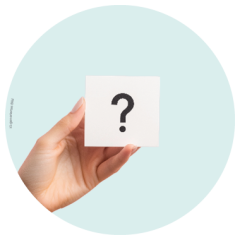 Eine Hand hält eine weiße Karte mit einem großen schwarzen Fragezeichen vor einem hellblauen runden Hintergrund.