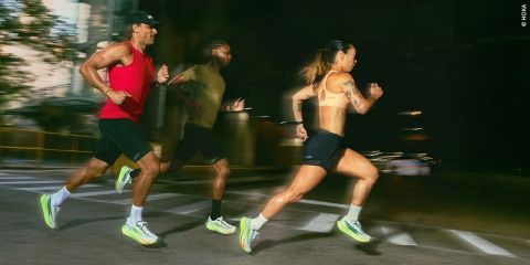 Drei Personen in Sportkleidung laufen gemeinsam auf einer nächtlichen Straße, sie wirken konzentriert und energiegeladen, wobei ihre Geschwindigkeit durch unscharfe Bewegungen verdeutlicht wird.