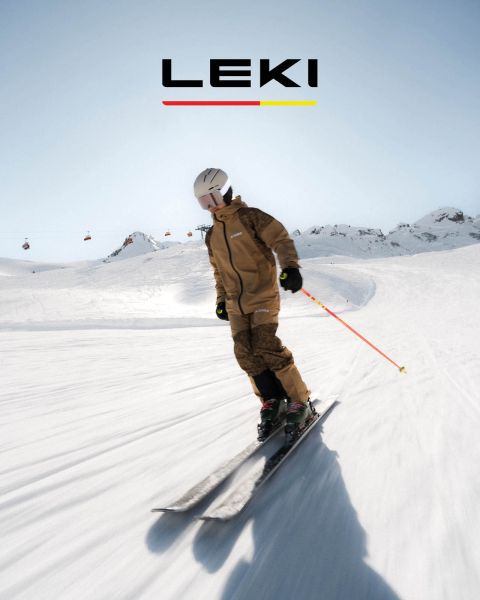 Ein Skifahrer in gelber Jacke und Skibrille fährt mit Stöcken einen verschneiten Berghang hinunter. Im Hintergrund sind schneebedeckte Berge und ein See zu sehen. Der Text lautet „WAS IST DEIN SPIELPLATZ? SPITFIRE 3D“ mit einem „JETZT ENTDECKEN“-Button.