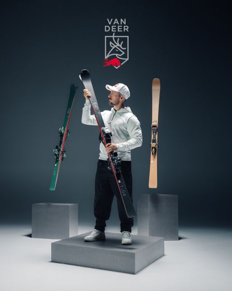 Zwei Paar Skier, zwei Skistöcke und ein Skischuh sind vor einem blauen Hintergrund mit dem Van Deer Logo und dem Text aufgehängt: "H-POWER 68 CARVE YOUR OWN PATH.