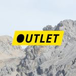 Das Wort „OUTLET“ in schwarzer Schrift auf einem gelben rechteckigen Hintergrund, vor einer felsigen Berglandschaft.